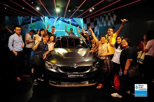 Participants taking a group photo beside a car